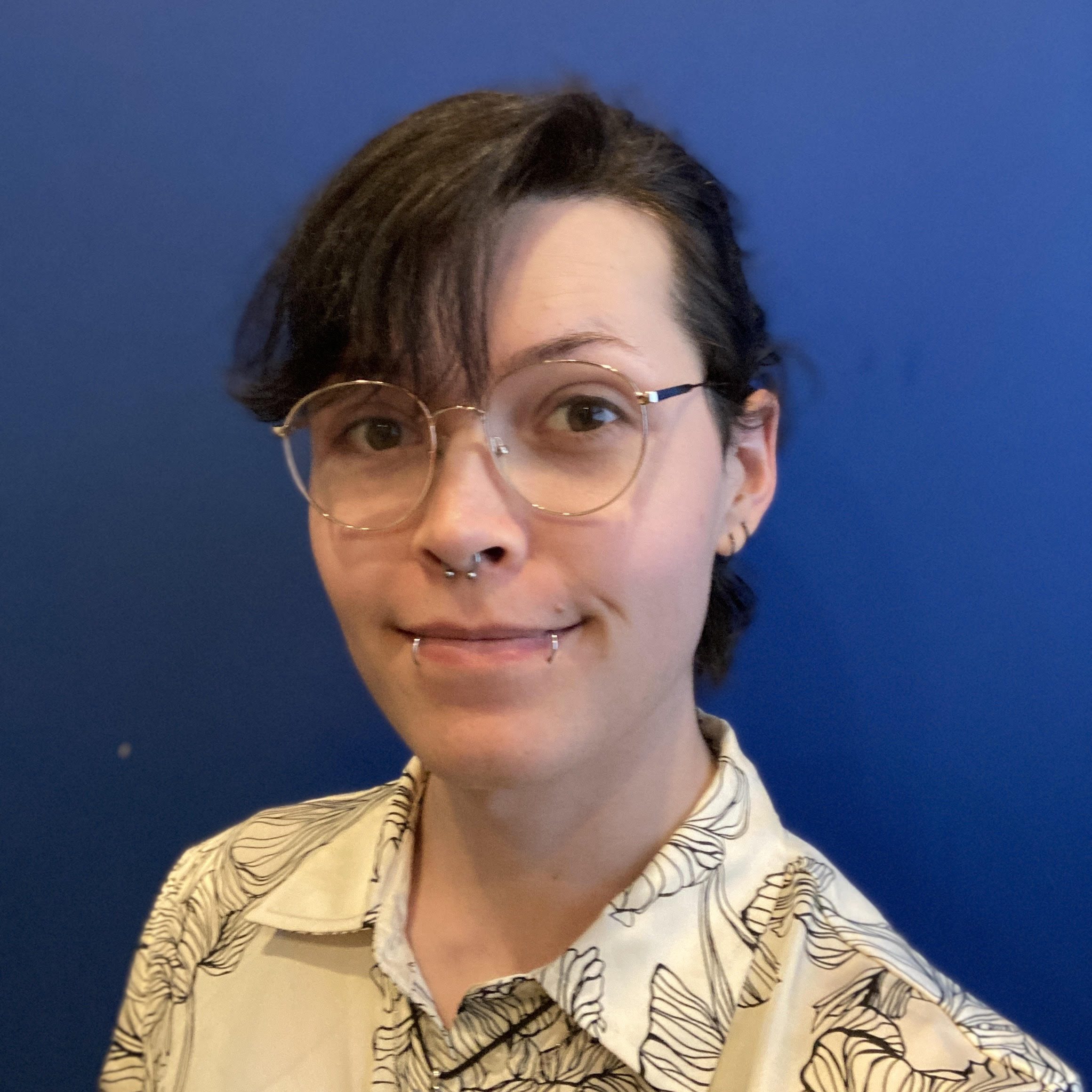Massage Therapy Firestone CO Eris Ledbetter Eris Ledbetter in front of a blue wall and wearing glasses